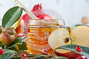 Rosh hashanah - jewish New Year holiday concept. Traditional symbols: Honey jar and fresh apples with pomegranate on white wooden