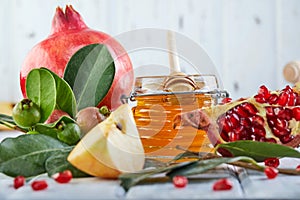 Rosh hashanah - jewish New Year holiday concept. Traditional symbols: Honey jar and fresh apples with pomegranate on white wooden