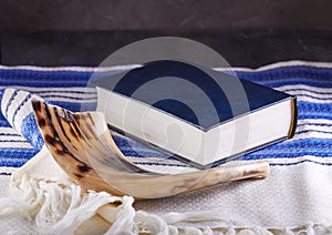 Rosh hashanah - jewish New Year holiday concept. Traditional symbols: Shofar - horn, tallite and Torah on a gray background