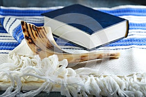 Rosh hashanah - jewish New Year holiday concept. Traditional symbols: Shofar - horn, tallite and Torah on a gray background