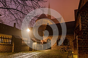 Roskilde cathedral and an illuminated yard with a bike a winter night