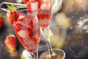 Rossini italian red alcoholic cocktail with sparkling wine, strawberry puree and ice in champagne glasses, copy space