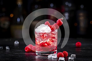 Rosso berry crush alcoholic cocktail drink with red vermouth, raspberries, currants and ice, dark bar counter background, copy