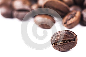 Rosted brown coffee beans lying on white background, selective focus