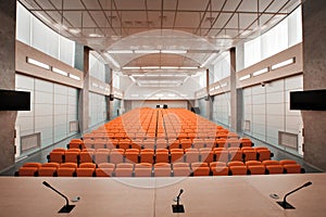 Rostrum with microphone and computer in conference hall. Orange color