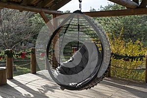 Rotang round hanging chair with grey pillow on outdoor backyard