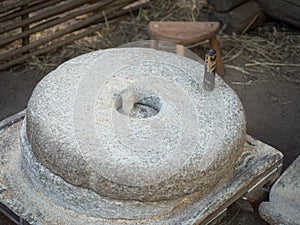 Rotary discoid mill stone for hand-grinding a grain into flour. Medieval hand-driven millstone grinding wheat. The photo