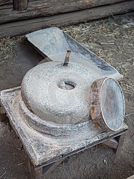 Rotary discoid mill stone for hand-grinding a grain into flour. Medieval hand-driven millstone grinding wheat. The photo