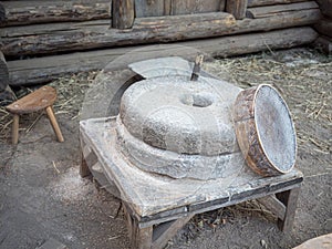 Rotary discoid mill stone for hand-grinding a grain into flour. Medieval hand-driven millstone grinding wheat. The photo