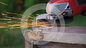 Rotary flex cutter cutting rusty nail on old wooden frame, sparks flying in air, closeup detail, slow motion video