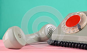 A rotary retro phone on a desk against a mint green wall