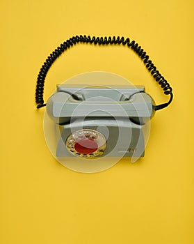 A rotary retro phone on a yellow background.