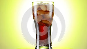 Rotated glass of Cola fizzy drink isolated on yellow background.