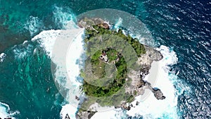 Rotating aerial drone clip of waves crushing unto the rocks. Little islet covered with birds from above. Overhead shot with slow z