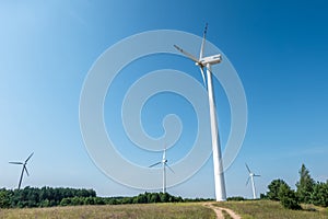 Rotating blades of a windmill propeller on blue sky background. Wind power generation. Pure green energy