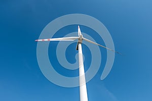 Rotating blades of a windmill propeller on blue sky background. Wind power generation. Pure green energy