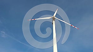 Rotating blades of a windmill propeller on blue sky background. Wind power generation. Pure green energy.
