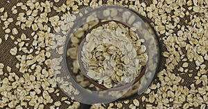 Rotating earthenware bowl with oat flake. Quality control of seeds using a magnifying glass. Flakes top view.