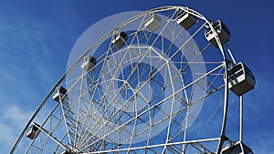Rotating Ferris wheel against the blue sky