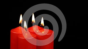 Rotating four red candles burning fire slowly spinning on a black background