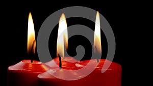 Rotating four red candles burning fire slowly spinning on a black background