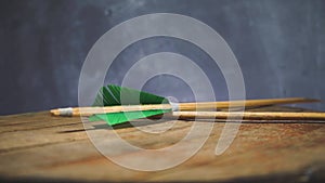 Rotating Old green wooden arrow on a round wooden table. Beautiful dark background