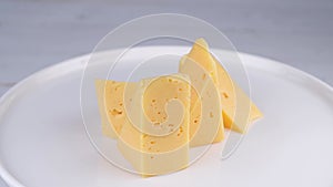 rotating pieces of hard cheese on a white plate or background close-up