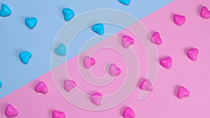 Rotating pink and blue background with heart shaped candies, concept of a gende party, trendy sweet background