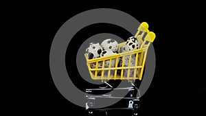 Rotating. quail eggs in a yellow shopping basket on a black background.