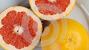 Rotating red grapefruit on a white plate closeup, macro shot.