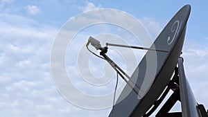 Rotating satellite dish, parabola, blue sky with clouds, text Sattelie services