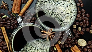 Rotating two cups with coffee on coffee beans and carica sticks