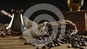 Rotating view of traditionally packed roasted coffee beans dispersed on wooddesk