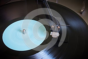 Rotating vinyl record with blue label on a turntable close-up