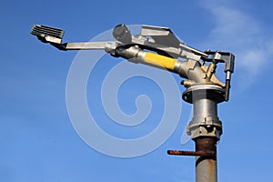 Rotating water spraying cannon against blue sky background