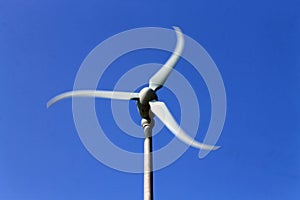 The rotating white windmil in the blue sky