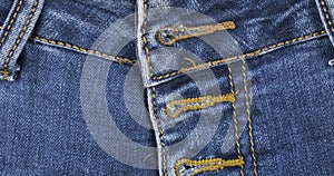 Rotation, close-up, detail of blue denim jeans, front view belt loop, pocket and button hole. Fashion background.