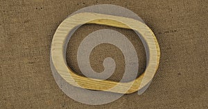 Rotation of an empty oval wooden frame lying on a burlap. Wooden frame on brown burlap background with beautiful brown