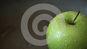 Rotation of a green apple with water drops