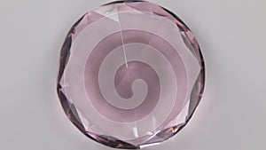 Rotation of a large pink rhinestone on a white background. Top view.