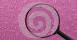 Rotation. Wind blowing on water drops on a pink background. Movement of a drop of water through a magnifying glass