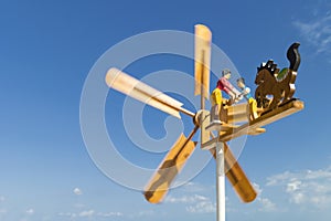 Rotation of a wooden weather vane with figures of people and painted blades against