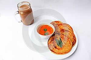 roti canai and teh tarik. paratha bread or canai bread or roti maryam, favorite breakfast dish. served on plate.