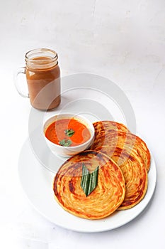 roti canai and teh tarik. paratha bread or canai bread or roti maryam, favorite breakfast dish. served on plate.