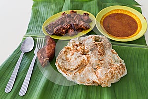 Roti prata on banana leaf with masala mutton, fish, curry