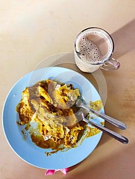 Roti ranai or roti parata with curry sauce and a cup of tea, popular Malaysian breakfast.