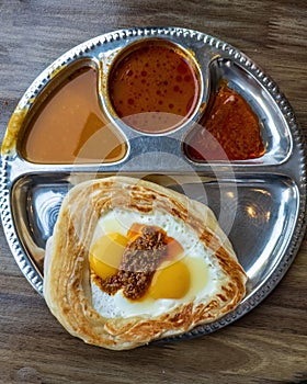 Roti Sarang Burung served with different gravies, pratha with half cook eggs in the middle