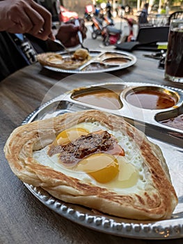 Roti sarang burung served with different gravies. It is pratha looks like bird nest with half cook eggs in the middle and topped