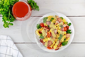 Rotini pasta, ham and vegetables with glass of tomato juice
