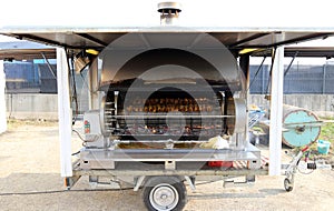 Rotisserie with wheels full of cockerels and roast chickens